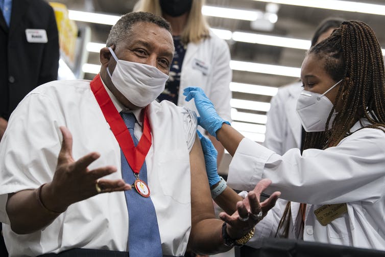 A man wearing a mask receives a COVID-19 vaccine booster.