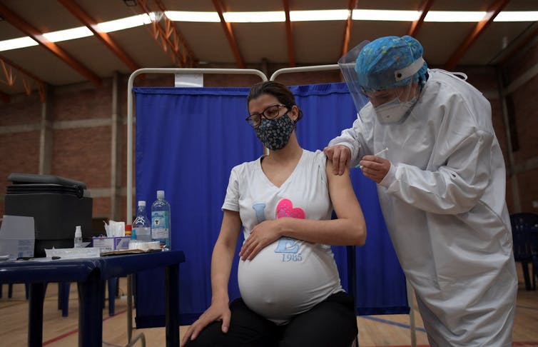 A pregnant woman receives the COVID-19 vaccine from her doctor.