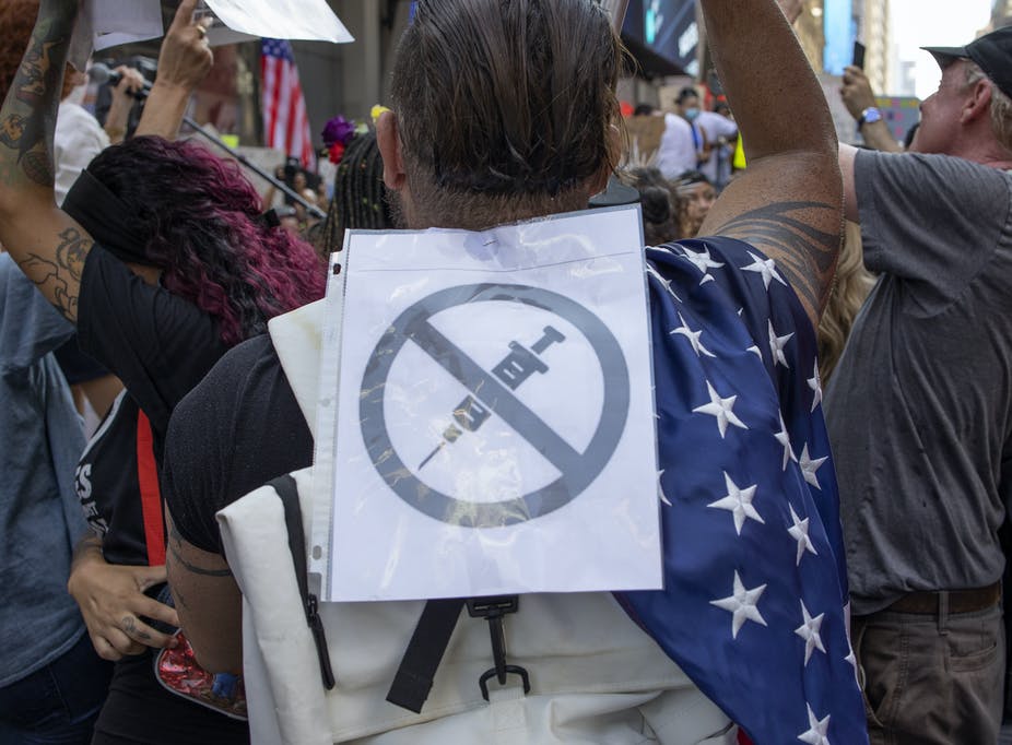 man at a rally with an anti-vaccine sign on his back
