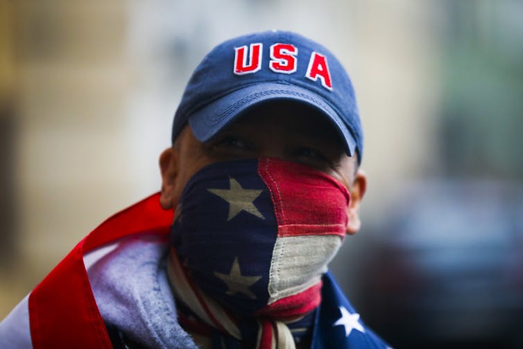 man in USA cap with American flag mask and another flag around shoulders