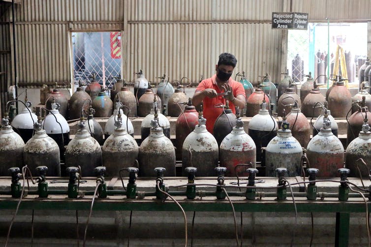 A worker refills oxygen gas tanks in India