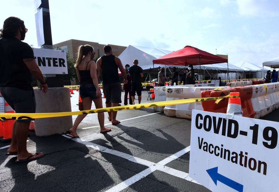 People standing in line at outdoors COVID-19 vaccination site.
