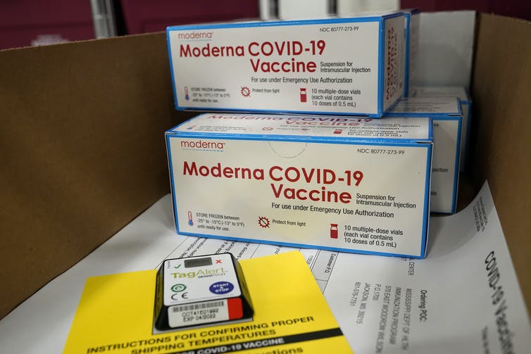 Four boxes of Moderna COVID–19 vaccines sitting on papers.