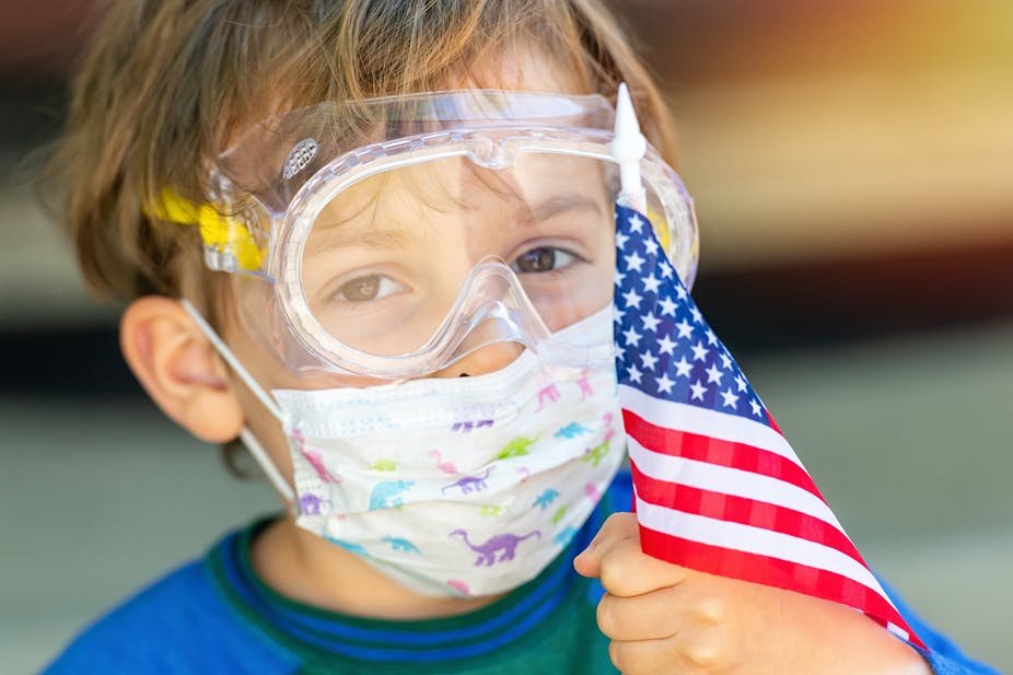 Boy wears protective mask, holds U.S. flag