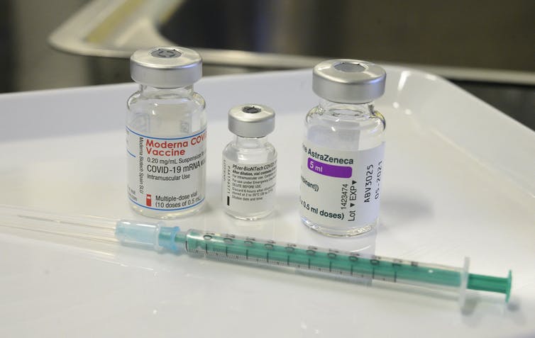 vials of three vaccines with syringe