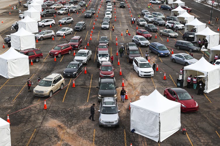 Cars wait in line to stop at vaccination tents.