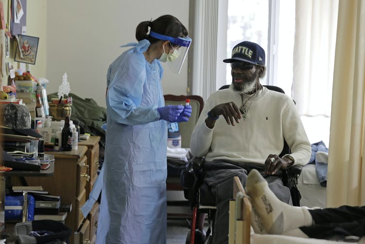 A healthcare worker administering a rapid test to an elderly man.