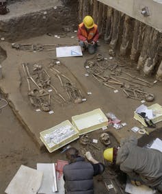 people excavating human skeletons from ground