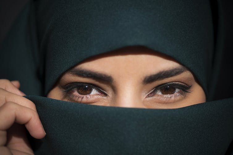 Close up of a woman wearing a niqab, who is clearly smiling.