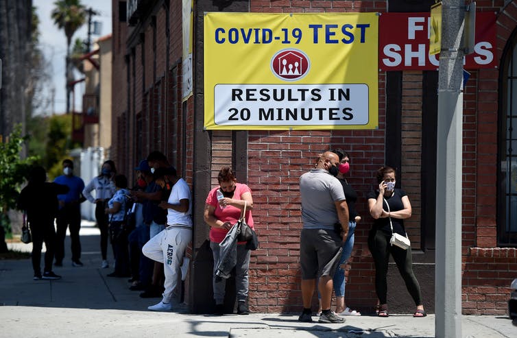 People stand in line at a clinic offering quick coronavirus testing near Long Beach, California.