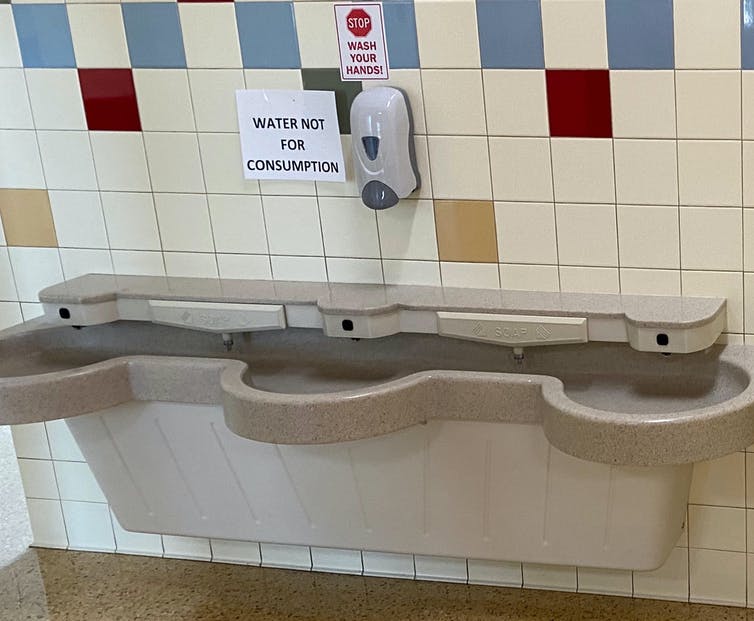A school restroom sink with a sign warning not to drink the water.