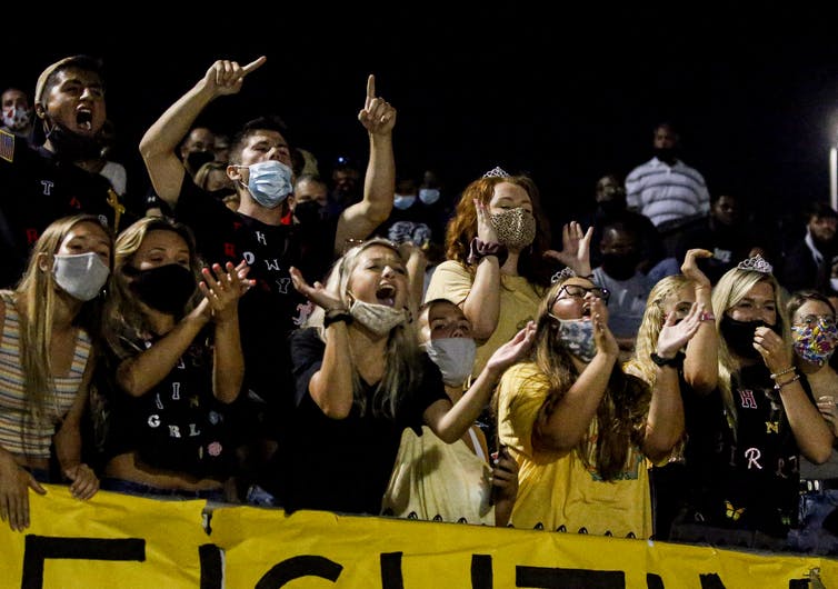 Students cheering at a high school football game.