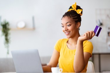 Black woman using computer and credit card at home
