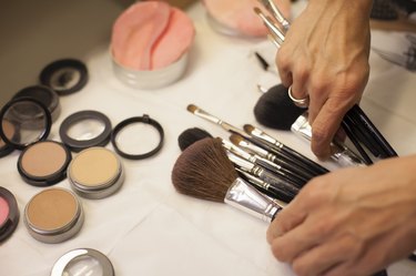 Make-up artist sorting through brushes on a table