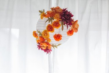 White hanging paper lantern with orange fall flowers.