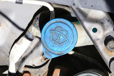 Windshield washer fluid access cap in a vehicle