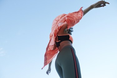 Fashionable woman wearing jacket with sports clothing against clear sky