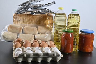 Basic food on a table storable for a long time. Eggs, oil, bread, tomato cans and bags of potato puere