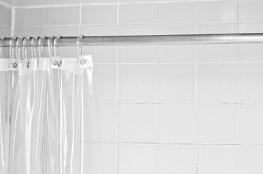 Clear shower curtain with a white tile shower