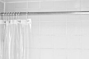 Clear shower curtain with a white tile shower