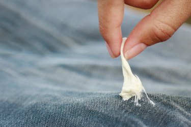 Close-Up Of Person Removing Bubble Gum From Jeans