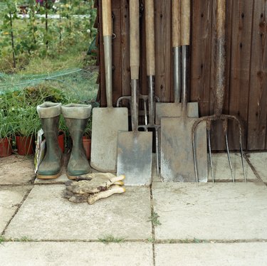 Spades, rake, boots and gardening gloves by a shed