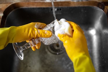 Washing a wine glass with dish soap and soft sponge