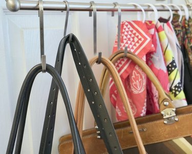 Purses and scarves hanging on the back of a closet door, organized on a rod with S-hooks.