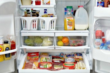 An open French-door, bottom-freezer refrigerator displaying its neatly organized contents.