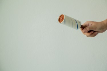 Cropped Hand Of Person Holding Adhesive Roller Against White Background