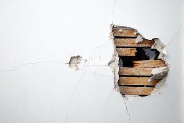 Cracked plaster, drywall and wood of a home's white wall