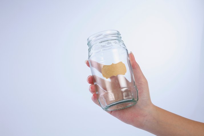 Hand Holding Glass Jar With Blank Label Against White Background