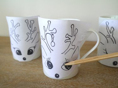 Templates taped to the mugs and a pencil outlining the image