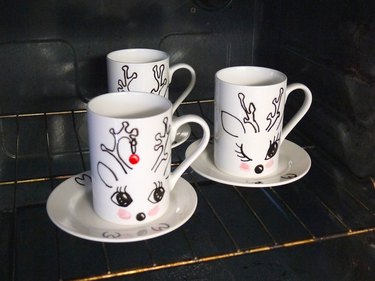 Three painted mugs in the oven ready for baking