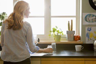 Woman looking out sunny window in kitchen