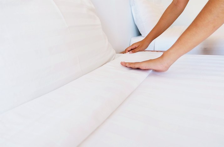 Cropped Hands Of Woman Adjusting Sheet On Bed