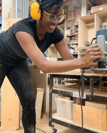 Smiling woman wearing headphones uses a woodworking saw
