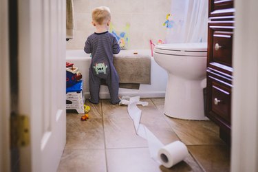 Baby playing with toilet paper in bathroom
