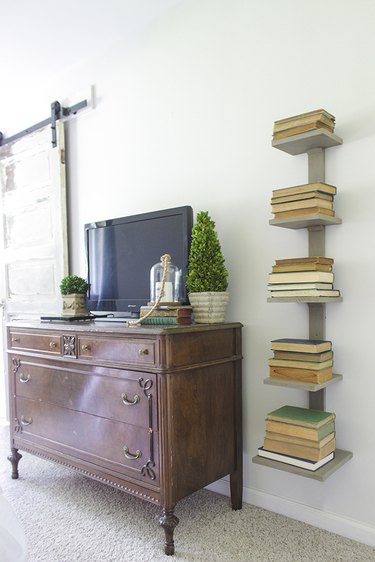 wall mounted spine bookshelf next to antique dresser.