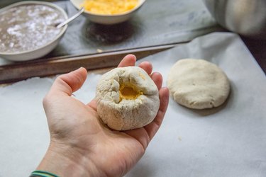 Folding papusa dough over cheese filling