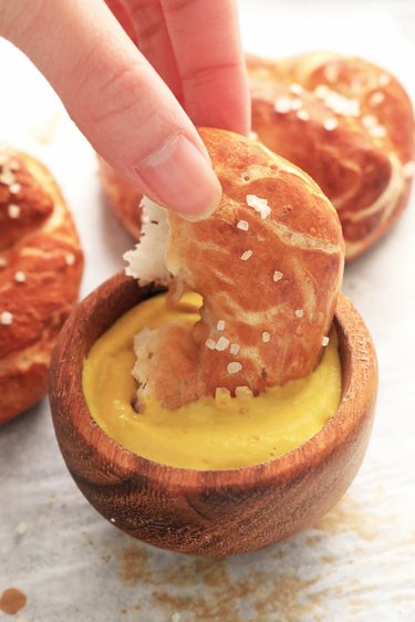 Dipping soft pretzel in mustard