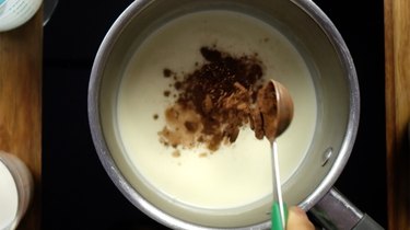 Adding cocoa into heavy cream in saucepan for sugar-free Irish cream liqueur.