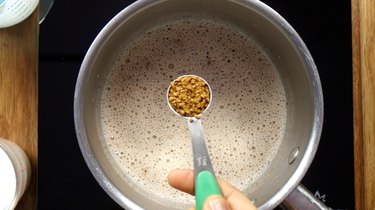 Adding instant coffee into heavy cream in saucepan for sugar-free Irish cream liqueur.