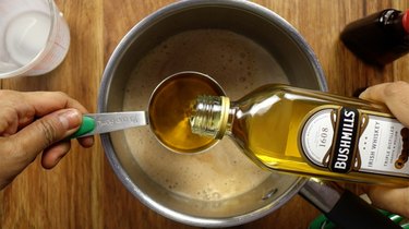 Adding whiskey into saucepan for sugar-free Irish cream liqueur.