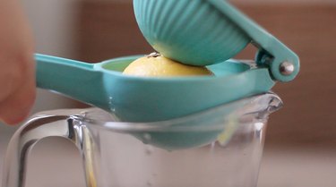 Squeezing lemon over measuring cup
