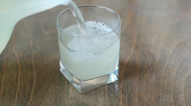 Pouring sparkling lemonade into ice-filled glass