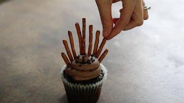 Inserting pretzel sticks into cupcake