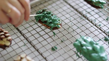 Smoothing melted green candy onto almonds