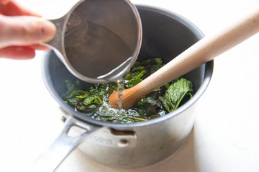 Pouring boiling water into saucepan with mint