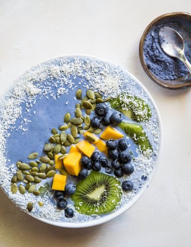Blue smoothie bowl with fruit and seeds on top